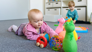 auf dem Boden krabbelndes Baby greift nach Spielsachen