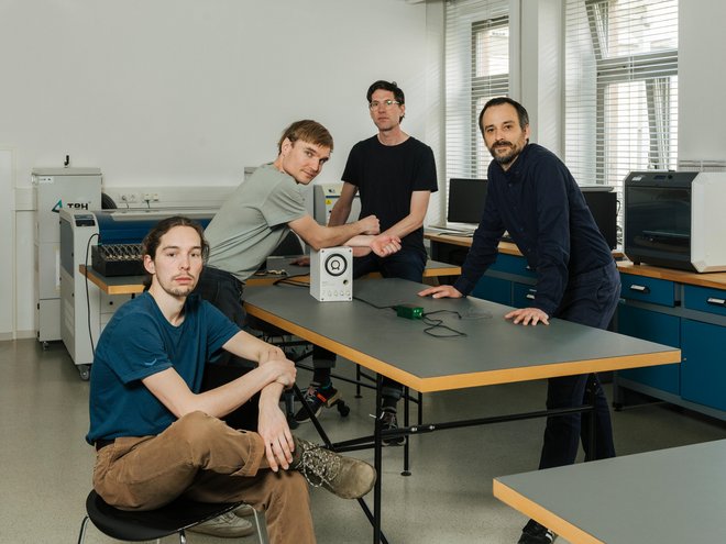 Photo of the research team at a table. A prototype of the new type of string lies on it.