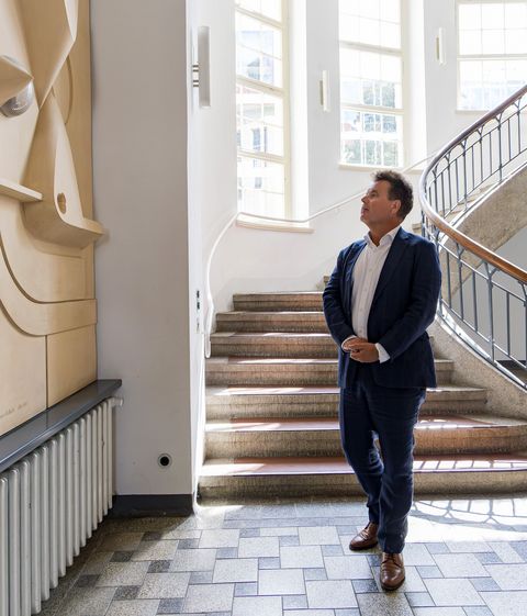 Foto: Matthias Eckert Jürgen Dusel, Bundesbeauftragter für die Belange von Menschen mit Behinderungen, zu Besuch an der Bauhaus-Universität Weimar Jürgen Dusel steht im Foyer des Hauptgebäudes, er ist alleine auf dem Foto zu sehen. Er betrachtet sehr interessiert ein Kunstwerk an der Wand: das Wandrelief Konfigurationen von Jost Schmidt von 1923 in einer Nachbildung von Hubert Schiefelbein 1976. Es ist sehr groß, abstrakt geometrisch mit verschiedenen hervorstehenden Formen, hell, aus Stuck und Glas. Schmidt studierte seit 1910 an der Hochschule für Bildende Künste in Weimar und war nach dem 1. Weltkrieg bis 1925 Meisterschüler der Werkstatt für Holzbildhauerei am Bauhaus in Weimar und Dessau. Zur Bauhaus-Ausstellung 1923 erarbeitete er drei abstrakt geometrische Wandreliefs für das Foyer. Eines davon wurde 1976 durch Hubert Schiefelbein rekonstruiert.
