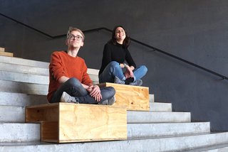 Foto zeigt Studierende sitzend auf Holzpodesten