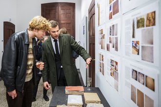 Second prize in the Research category: Vincent Hummelberger explains his thesis on surface finishing in interior and exterior clay panel construction in the exhibition (Photo: Thomas Müller, Copyright: Bauhaus-Universität Weimar)