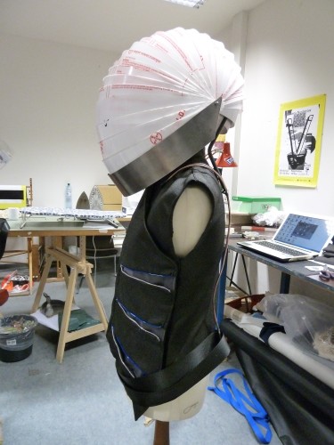 side view finished vest and helmet (protective coat still on); basic wire frame structure for O² pack, that holds up helmet