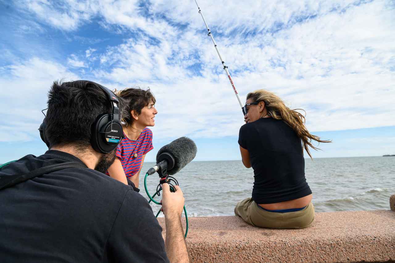 an interview setting featuring one individual wearing an audio headset including a microphone and another individual wielding a fishing rod