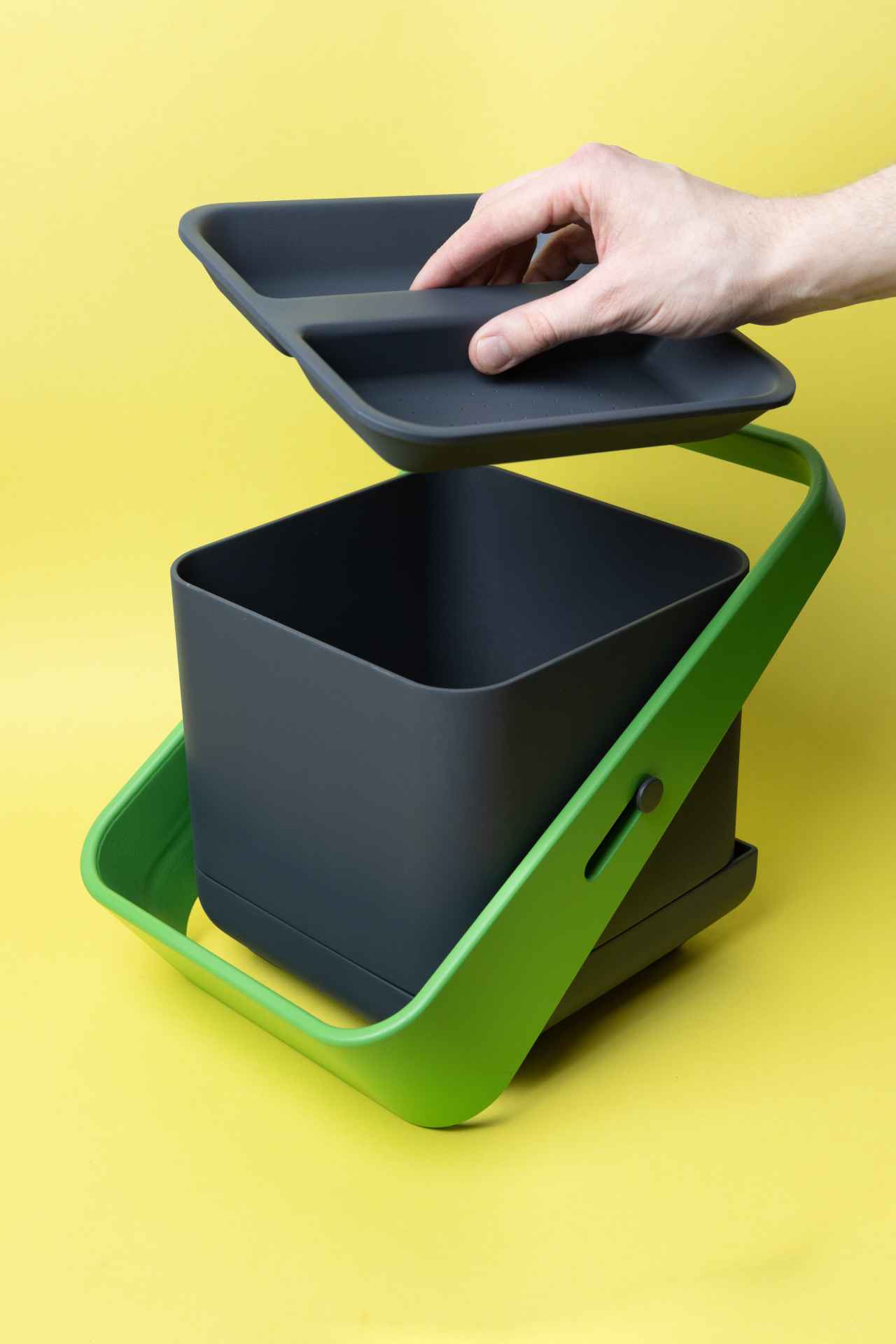 CUBIO with handle in diagonal position, hand lifting the lid