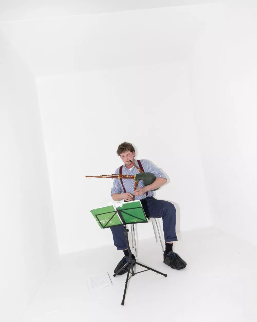 eine Person, die in einem einfachen, schmucklosen Raum auf dem Dudelsack spielt