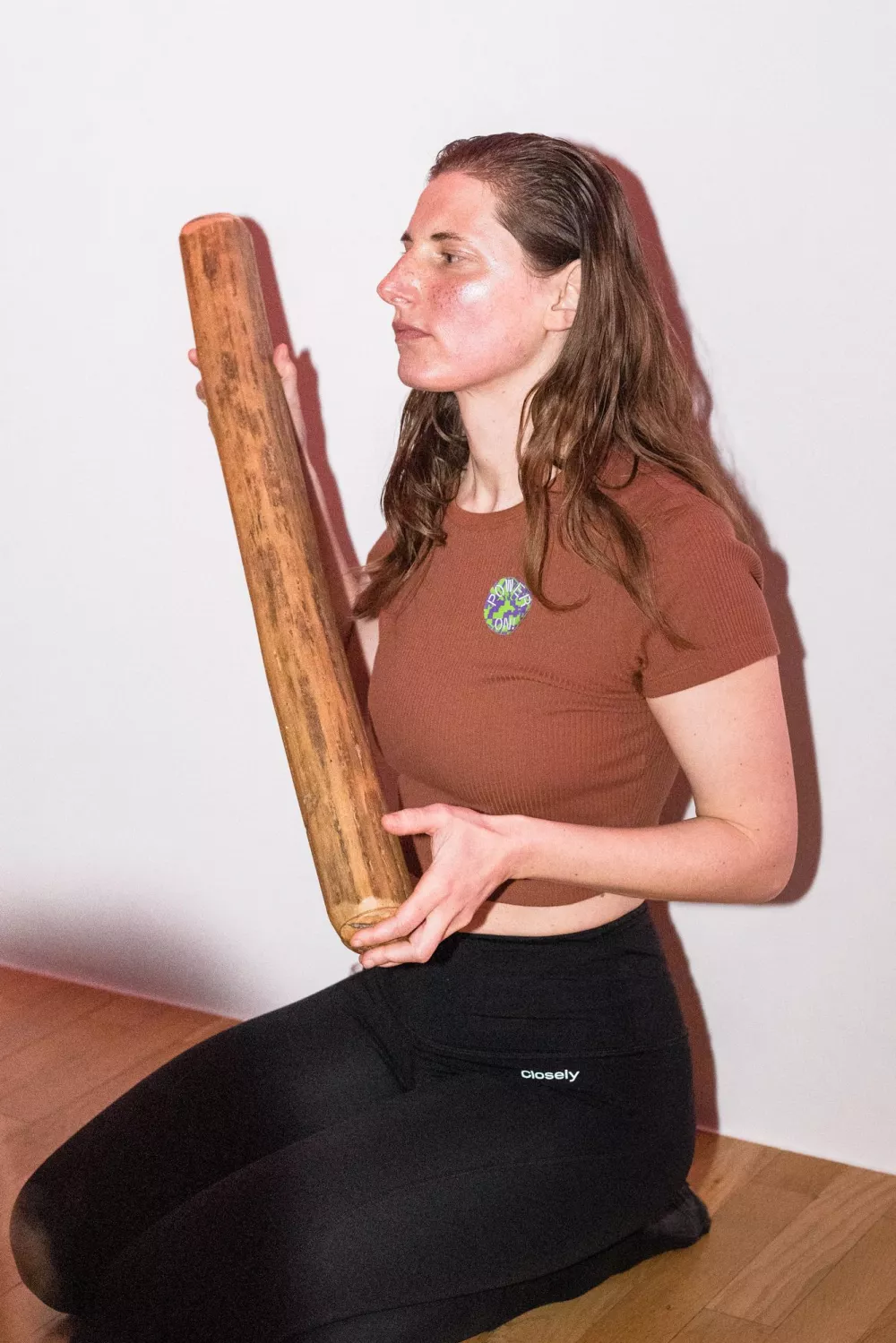 eine kniende Person, die ein Stück Holz hält