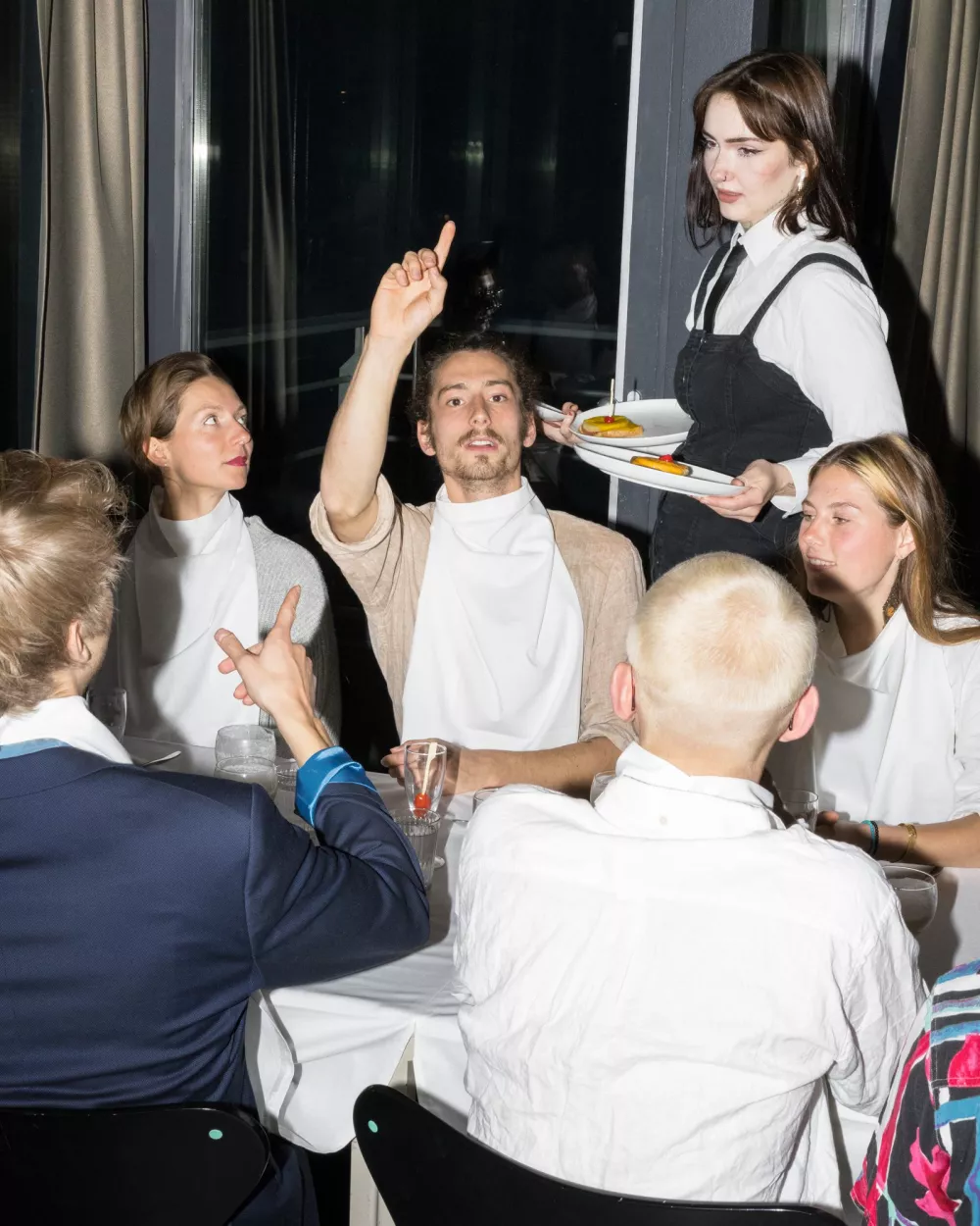 Personen, die an einem Tisch sitzen und denen Essen serviert wird