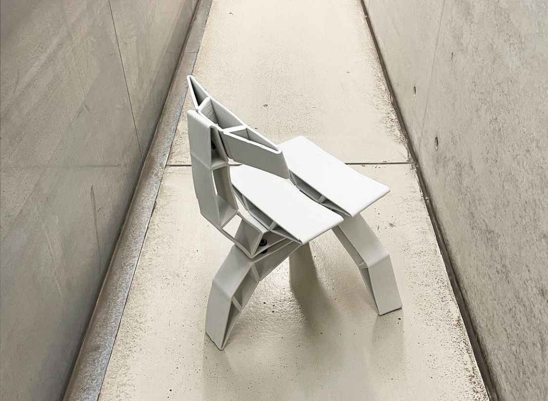 assembled ceramics chair standing in front of a concrete wall, rear-view