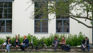 Außenansicht des Gebäudes der Fakultät Gestaltung in der Geschwister-Scholl-Straße 7. Studierende sitzen auf einer Bank vor dem Haus. (Foto: Candy Welz)