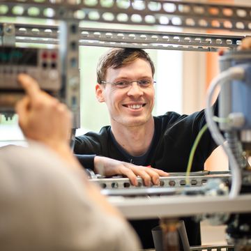 Man stands at a technical apparatus and looks into the camera