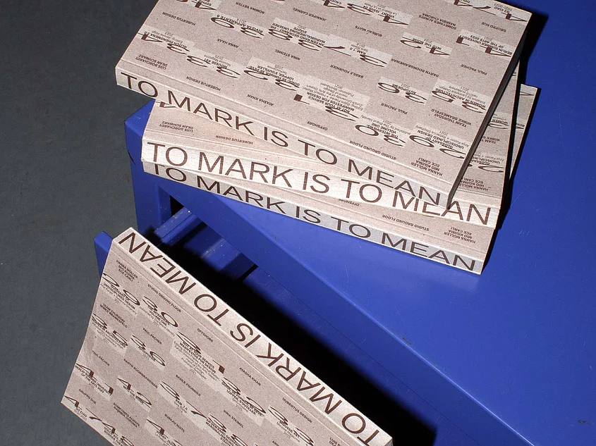 »To Mark is to Mean«: Several copies of the publication are displayed on a blue piece of furniture. The cover and spines feature typographic designs. Photo: Emelie Grannert