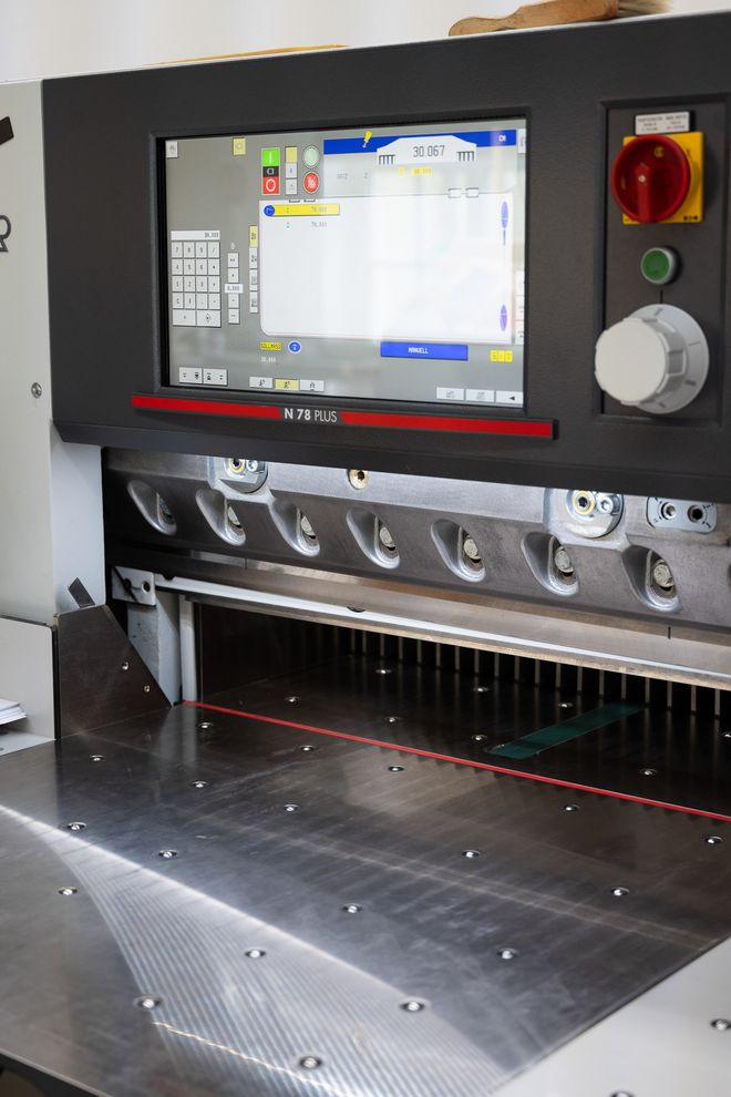 Schneidemaschine mit digitalem Bedienpanel und großem Schneidetisch zum präzisen Zuschneiden von Papierstapeln.