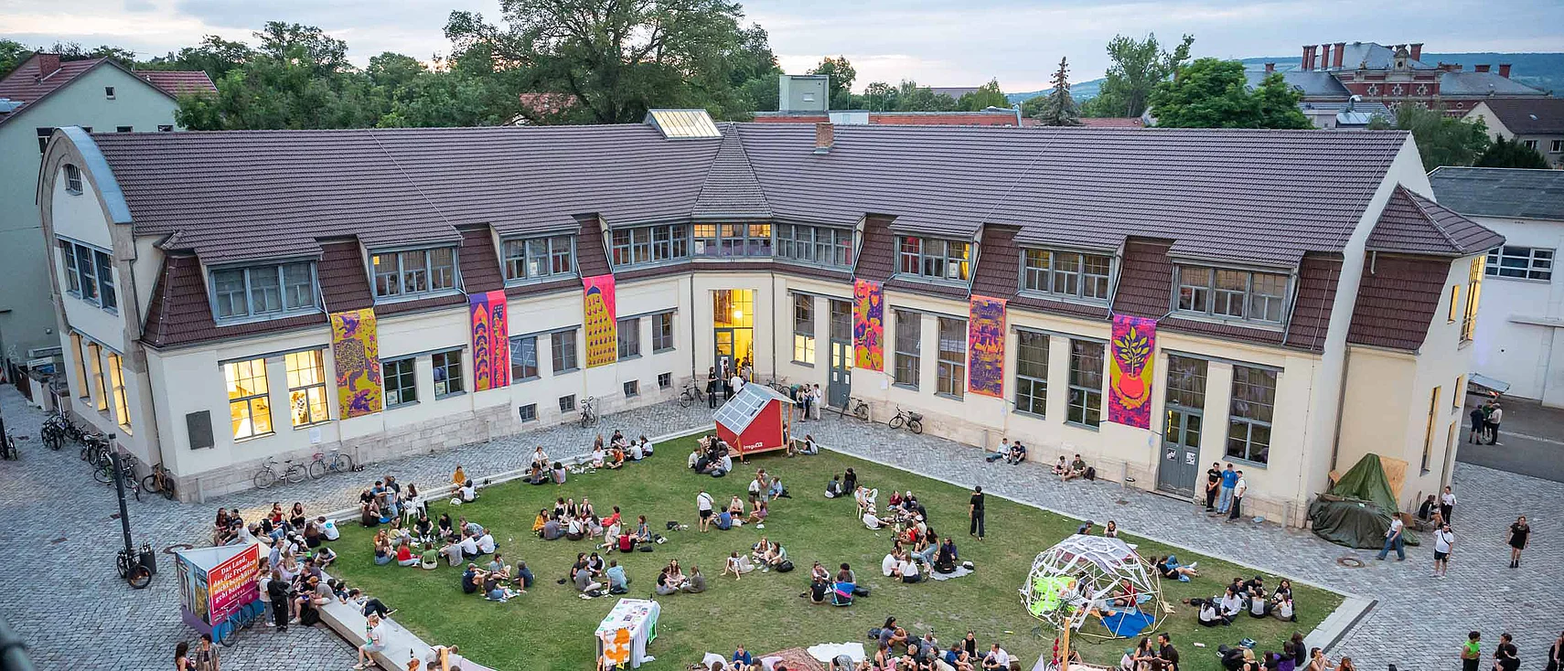 The outdoor area in front of the Van de Velde Building during the summaery. Students and visitors gather among installations and presentations.