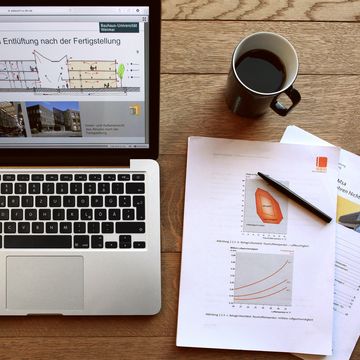 Aufgeklappter Laptop, Kaffeetasse, Arbeitsunterlagen