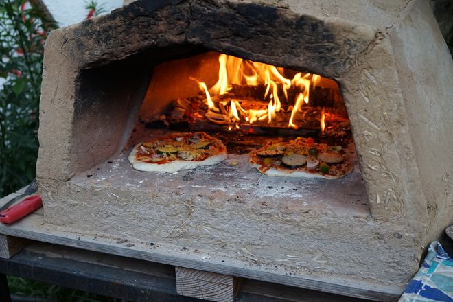 Two pizzas are baking in the KüfA oven.