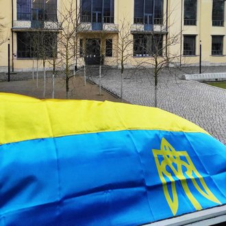 Blick aus dem International Office auf das Hauptgebäude der Universität mit ukrainischer Flagge im Vordergrund