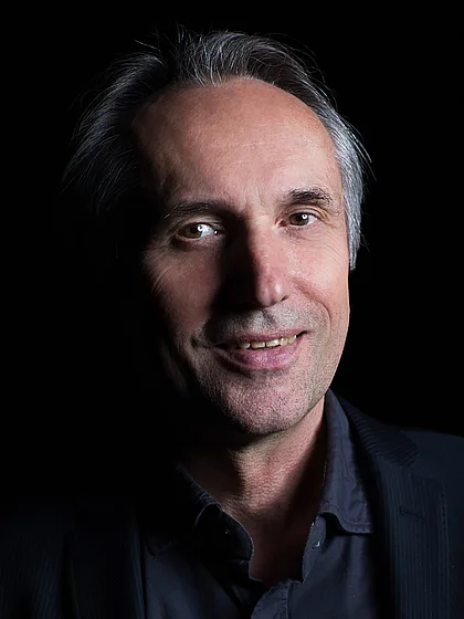 Portrait photograph of Micky Remann against a black background