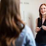 Professorin steht vor Tafel und unterhält sich angeregt mit einer weiteren Frau. 