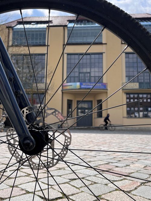 Hauptgebäude durch die Speichen eines Fahrrads fotografiert