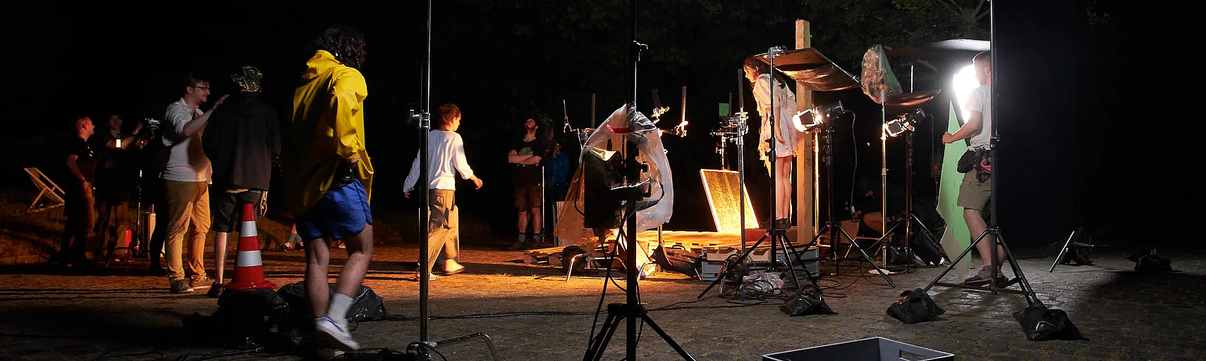 Film set during a night shoot for »Refugium«. The film crew works among numerous lights, stands and other filming equipment.