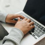 Person typing on a laptop, close-up of hands and keyboard