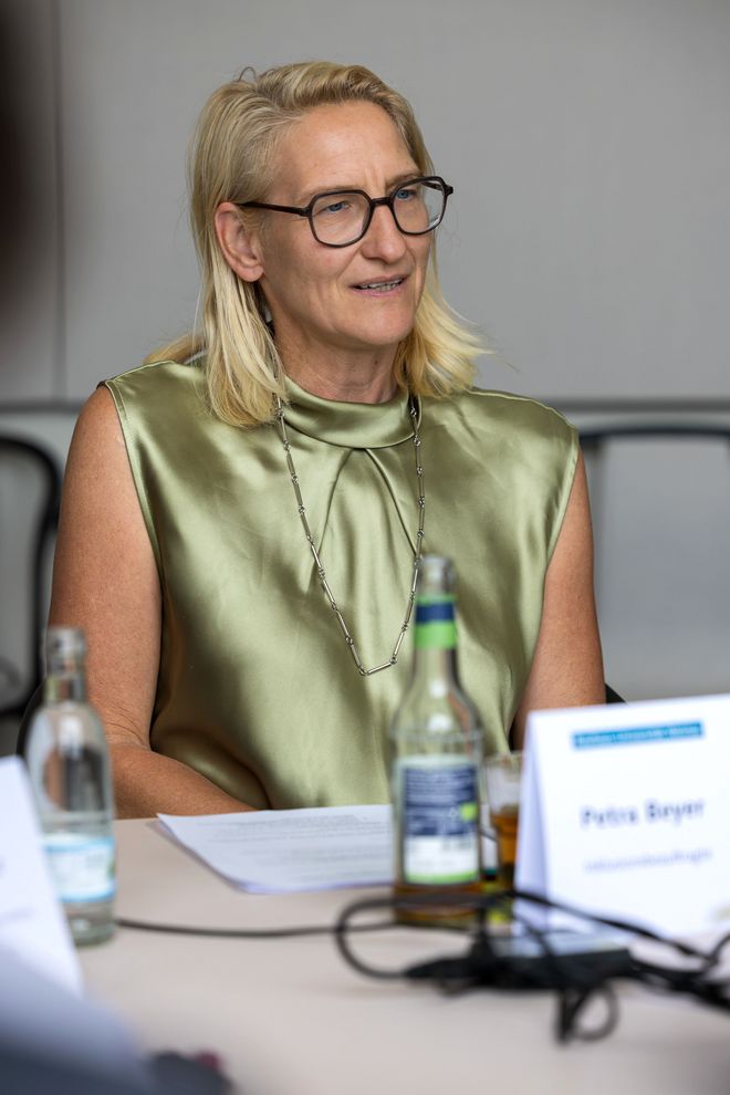 Die Inklusionsbeauftragte Petra Beyer spricht und sieht dabei konzentriert und interessiert aus. Sie sitzt am Besprechungstisch.