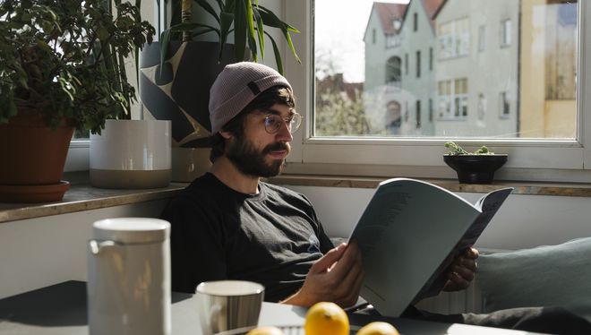 Junger Mann mit Zeitschrift am Küchentisch. Foto: Dominique Wollniok