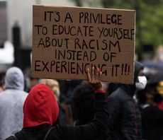 Das Foto zeigt eine Anti-Rassismus-Demo. Eine Person hält ein Schild hoch mit der Botschaft: It's a privilege to educate yourself about racism instead of experiencing it!!!