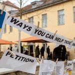 Blätter, auf Leine aufgehängt vor dem Studierendenhaus M18, mit dem Schriftzug: Ways you can help.