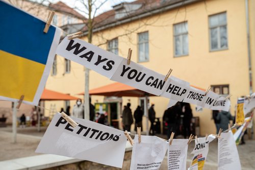 Sheets, hung on lines in front of the student house M18, with the writing: Ways you can help.