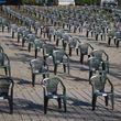 Photo: Adrian Bancu; Source: Pexels Numerous dark grey plastic monobloc chairs are arranged in regular rows on a paved outdoor area.