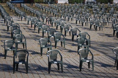 Einreichungen bis 5. Oktober 2026 möglich: Zahlreiche dunkelgraue Monoblock-Stühle aus Kunststoff stehen in regelmäßigen Reihen auf einer gepflasterten Fläche im Freien.