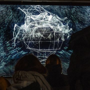 Bildschirm mit digitaler Grafik von Prof. Ursula Damm, auf den Personen schauen. Foto: Thomas Müller