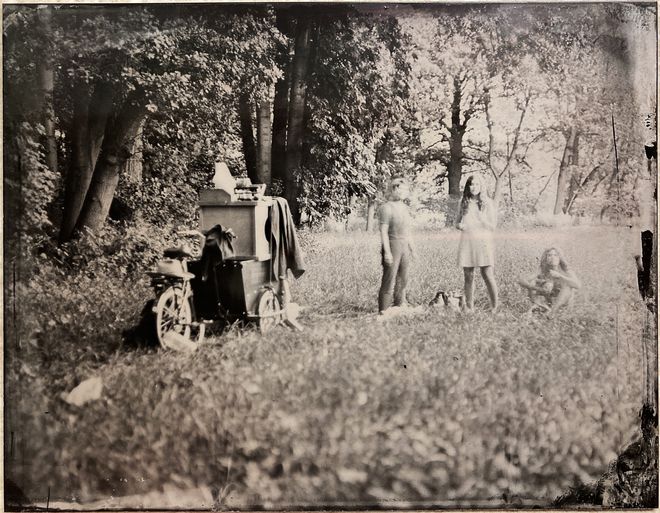 Sepia-Foto der mobilen Dunkelkammer auf einer Wiese, zwei Perosonen sind auf dem Bild zu sehen