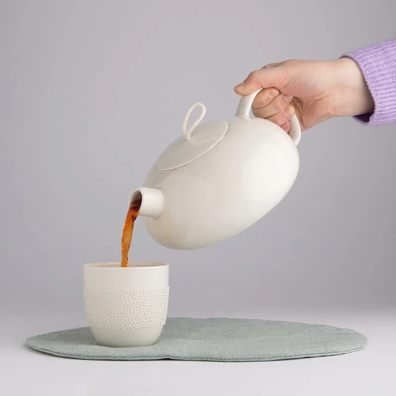 Teekanne füllt Tee in Tasse