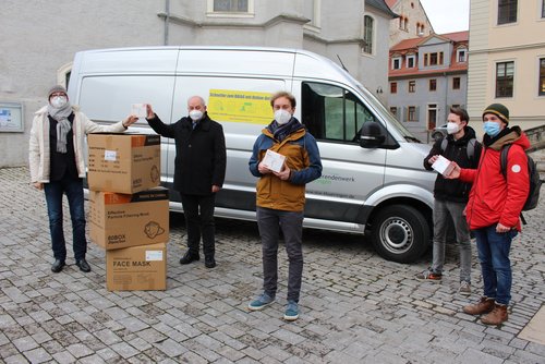 Five persons with boxes of masks outdoors