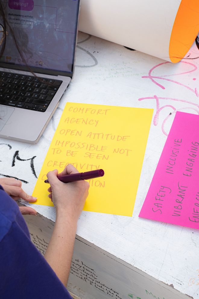 eine Person schreibt Worte auf ein buntes Blatt Papier