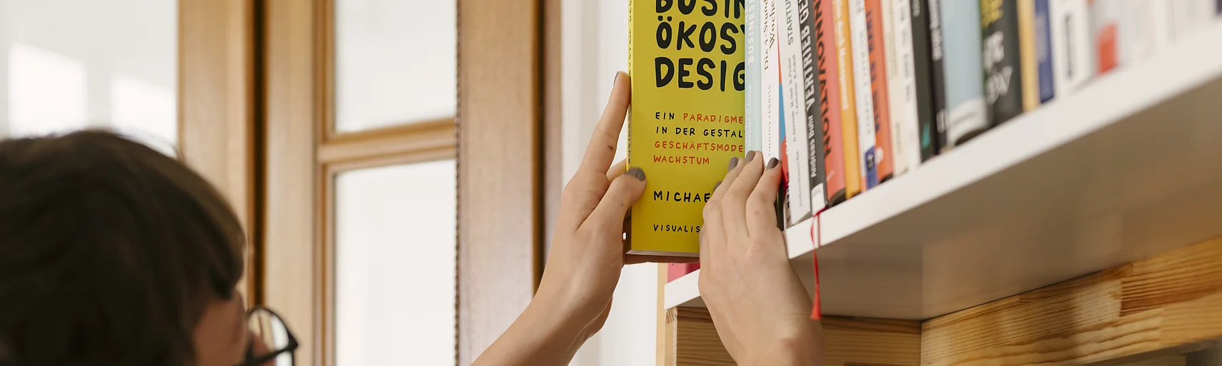 Person schiebt Buch in Schrank