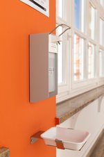 Disinfectant dispenser in front of an orange wall