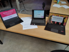 Photo of three laptops on the table of a seminar room. The screen of the computer to the left reads: »Jägerinnen und Sammler: Evolutionsgeschichte zur Menschwerdung — Sigrid Schmitz« (»Female Hunters and Gatherers: An Evolutionary History of the Process of Becoming Human — Sigrid Schmitz«). The screen of the computer to the left reads: »Gender and Biology: Genetik — Einführung in ›objektive Wissenschaften‹« (»Gender and Biology: Genetics — Introduction to ›Objective Sciences‹«). The screen of the computer to the right reads: »Technik und Gender: Männer- und Frauengehirne. Und wie Geschlecht ins Gehirn kommt« (»Technology and Gender: Men’s and Women’s Brains. And How Gender Ends Up in the Brain«).