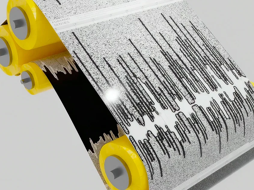 A digital 3D rendering of a black-and-white track featuring organic-looking linear patterns, which runs over several bright yellow rollers.