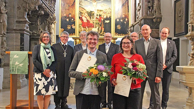 Award recipients of the Herder Förderpreis at the Stadtkirche St. Peter und Paul (Herderkirche) in Weimar. Sarah Steingrüber and main prize winner Jonas Kahl stand with certificates and bouquets in front of representatives of the participating institutions.