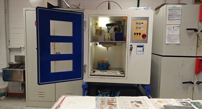 Industrieofen mit geöffneter Tür in einem Werkraum. Im Inneren sind Formen und Materialien auf einer Ablagefläche sichtbar.