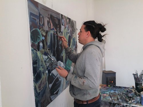 Simon Surjasentana works on a painting with a brush in his hand