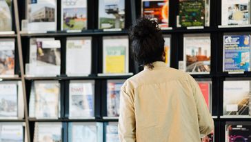 Mann von hinten fotografiert vor einem Bücherregal