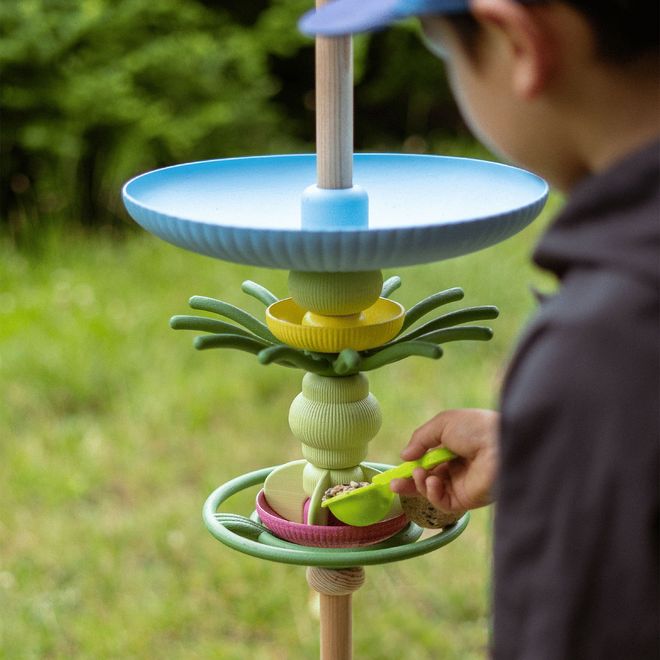 Ein Kind füllt Vogelfutter in die Station ein