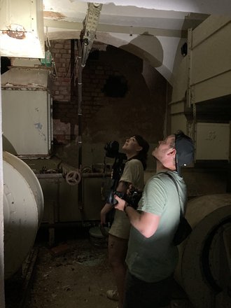 Zwei Personen mit Fotoapparaten in einem dunklen Keller