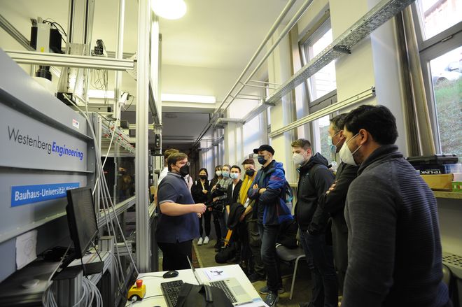 Teilnehmende des Science Camps vor dem Windkanal, Johannes Fülöp, TU Ilmenau, erklärt. (Quelle: Bauhaus-Universität Weimar, Foto: Stefanie Waske)