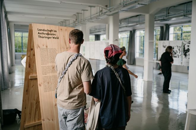 Ausstellungsbesuchende lesen aufmerksam die Projektbeschreibung»Landschaft im Anthropozän – Thüringer Wald«