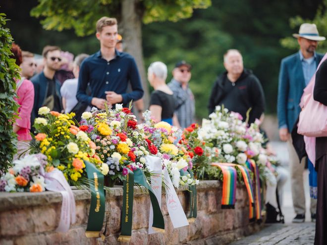 Mourning bouquets lined up on a small wall at the entrance to the Buchenwald Memorial.